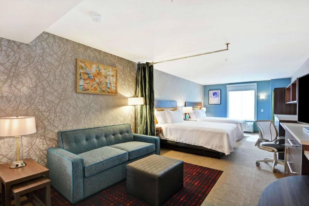 Una habitación de hotel con una cama, un sofá, un escritorio y una lámpara.
