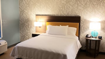 Habitación de hotel con una cama grande, dos lámparas de noche, un teléfono en la mesita y un calentador de pared.