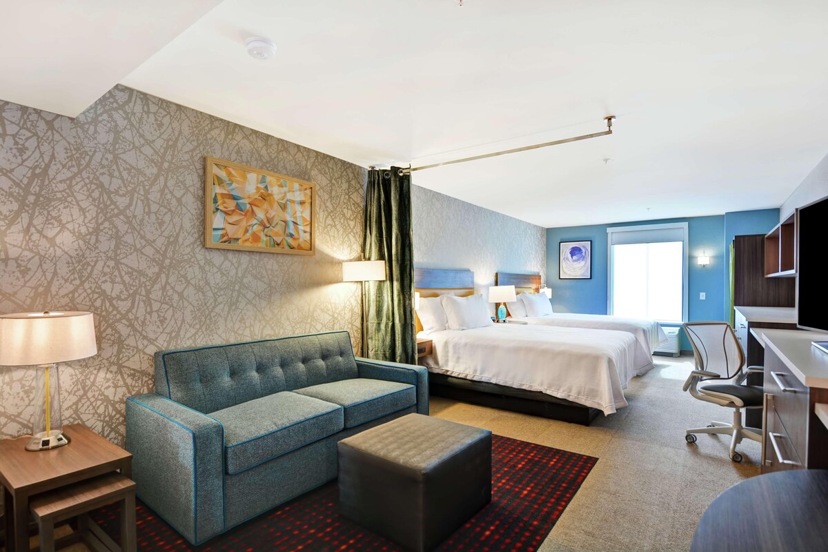 Een hotelkamer met een bed, een bank, een bureau en een lamp.