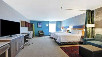 Una habitación de hotel con escritorio, televisor, dos camas, una silla y un sofá.