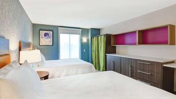 A hotel room with two beds, a window with a view, a green curtain, and a cabinet with drawers.