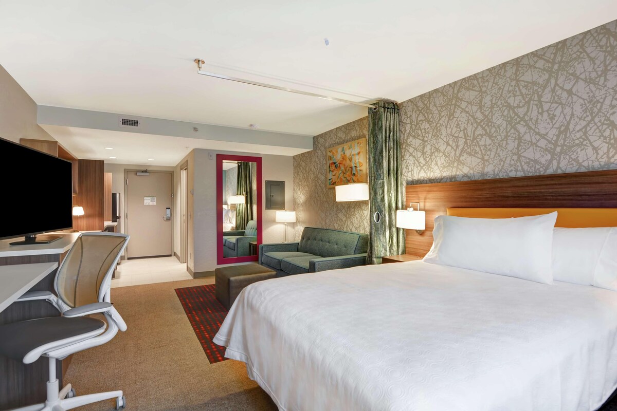 Een hotelkamer met een groot bed, een bureau met stoel, een bank en een televisie.