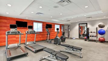 A gym with treadmills, elliptical machines, and weight benches.