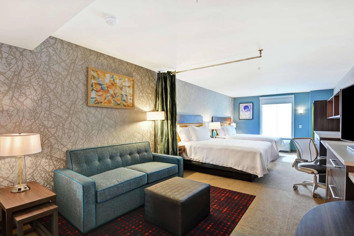 Una habitación de hotel con cama, sofá, escritorio y una silla.