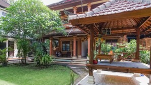 Uma casa de madeira tradicional com telhado de telhas, varanda coberta e um jardim bem cuidado.