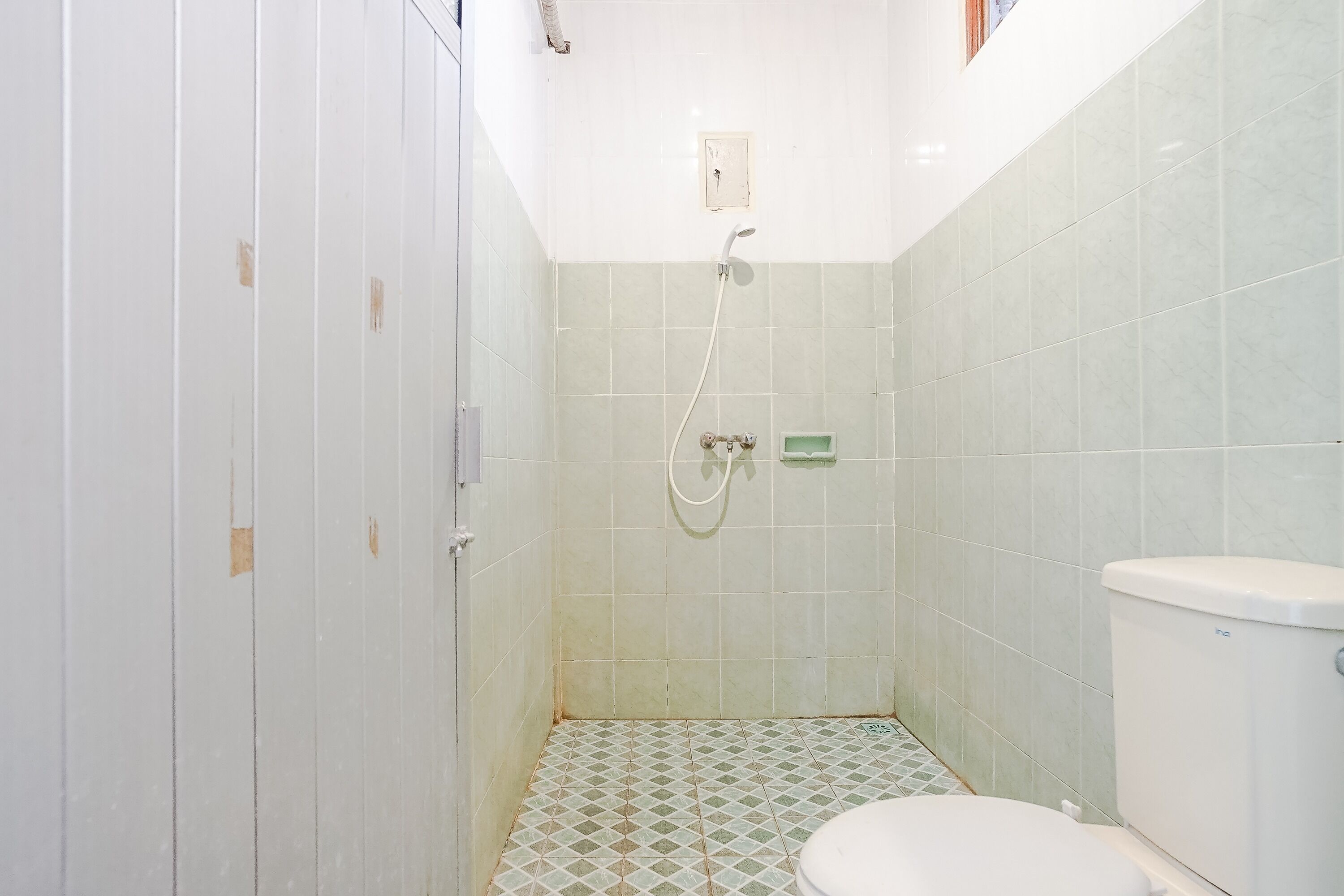 A small bathroom with a toilet, a shower, and tiled walls.