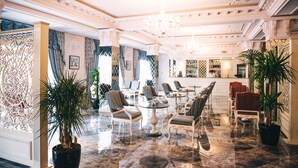 A spacious lobby with ornate columns, a bar area, and several seating arrangements. - Emerald Suite Hotel (Baku)