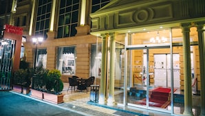 A hotel entrance with large glass doors, columns, and a red carpet leading inside. - Emerald Suite Hotel (Baku)