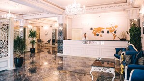 A reception area with a marble floor, a world map on the wall, and a receptionist behind the counter. - Emerald Suite Hotel (Baku)