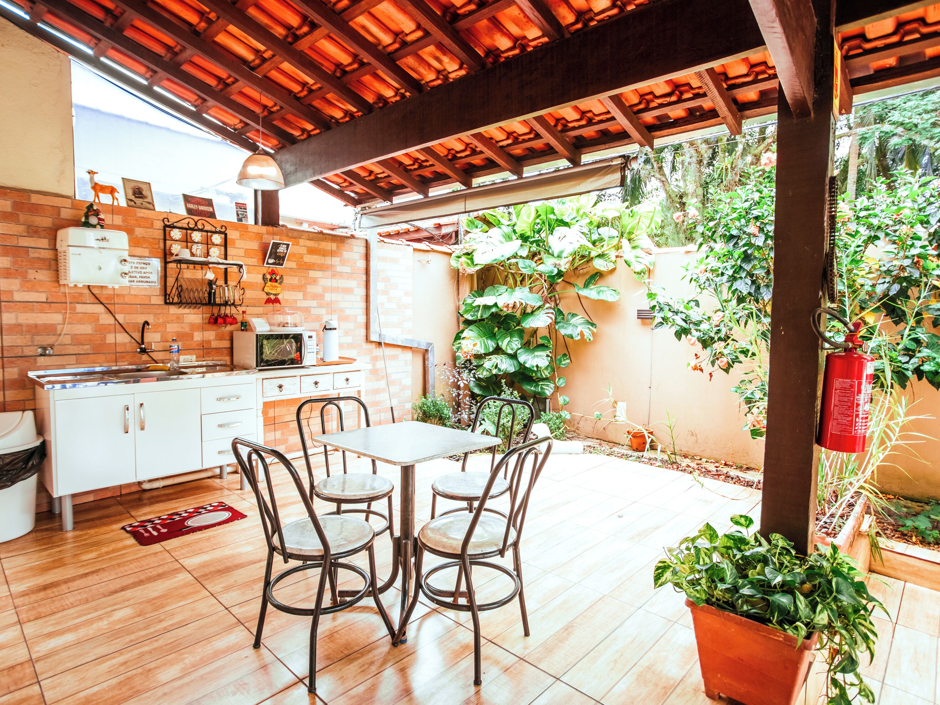 A kitchen with a microwave, sink, and cabinets. There is a table with chairs and a fire extinguisher.