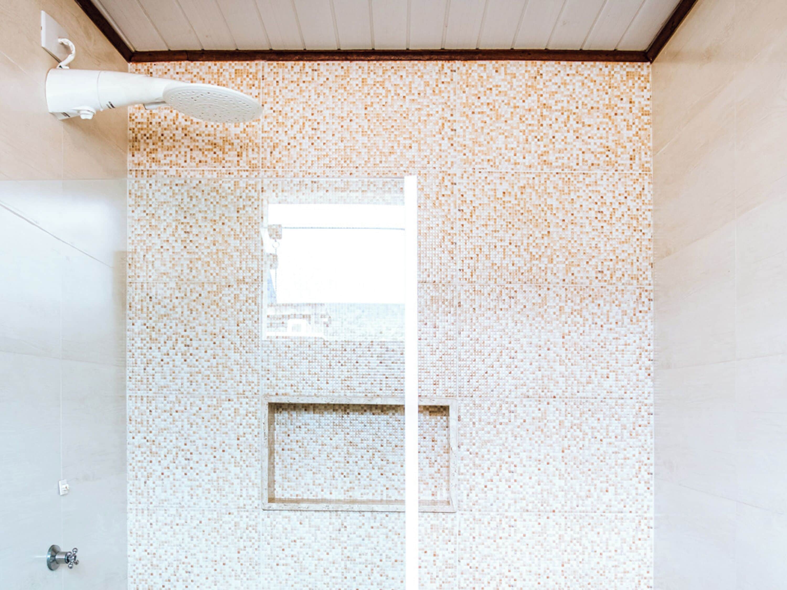 Une salle de bain avec des murs recouverts de mosaïques, une fenêtre et un porte-serviettes.