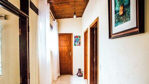 A hallway with a wooden ceiling, a tiled floor, and a door at the end. - VELINN Pousada Praia do Perequê (Ilhabela)
