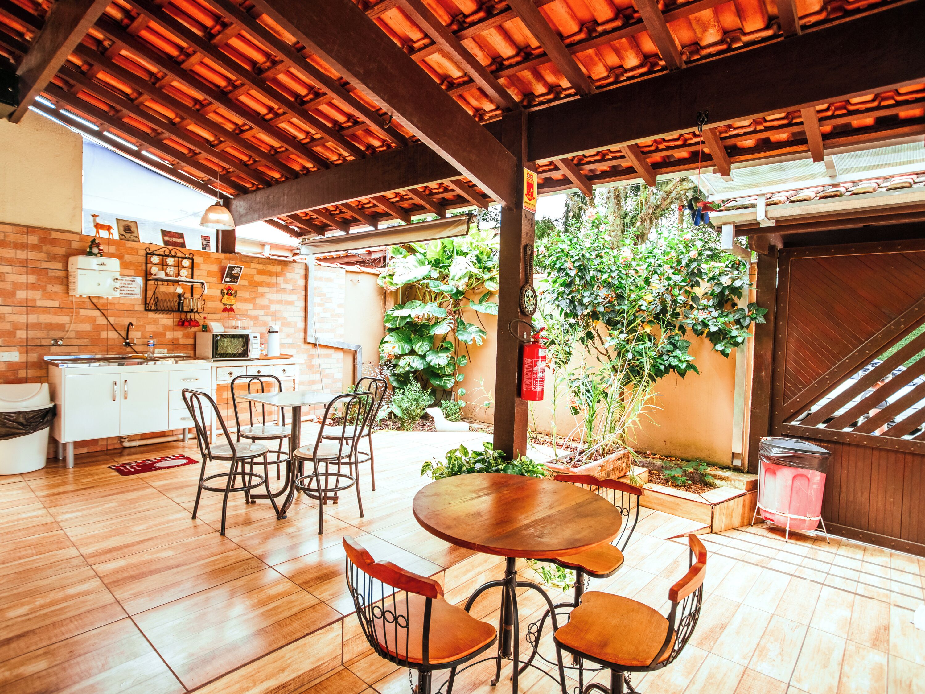 Une terrasse avec une table et des chaises en bois, un mur en briques et une plante en pot.