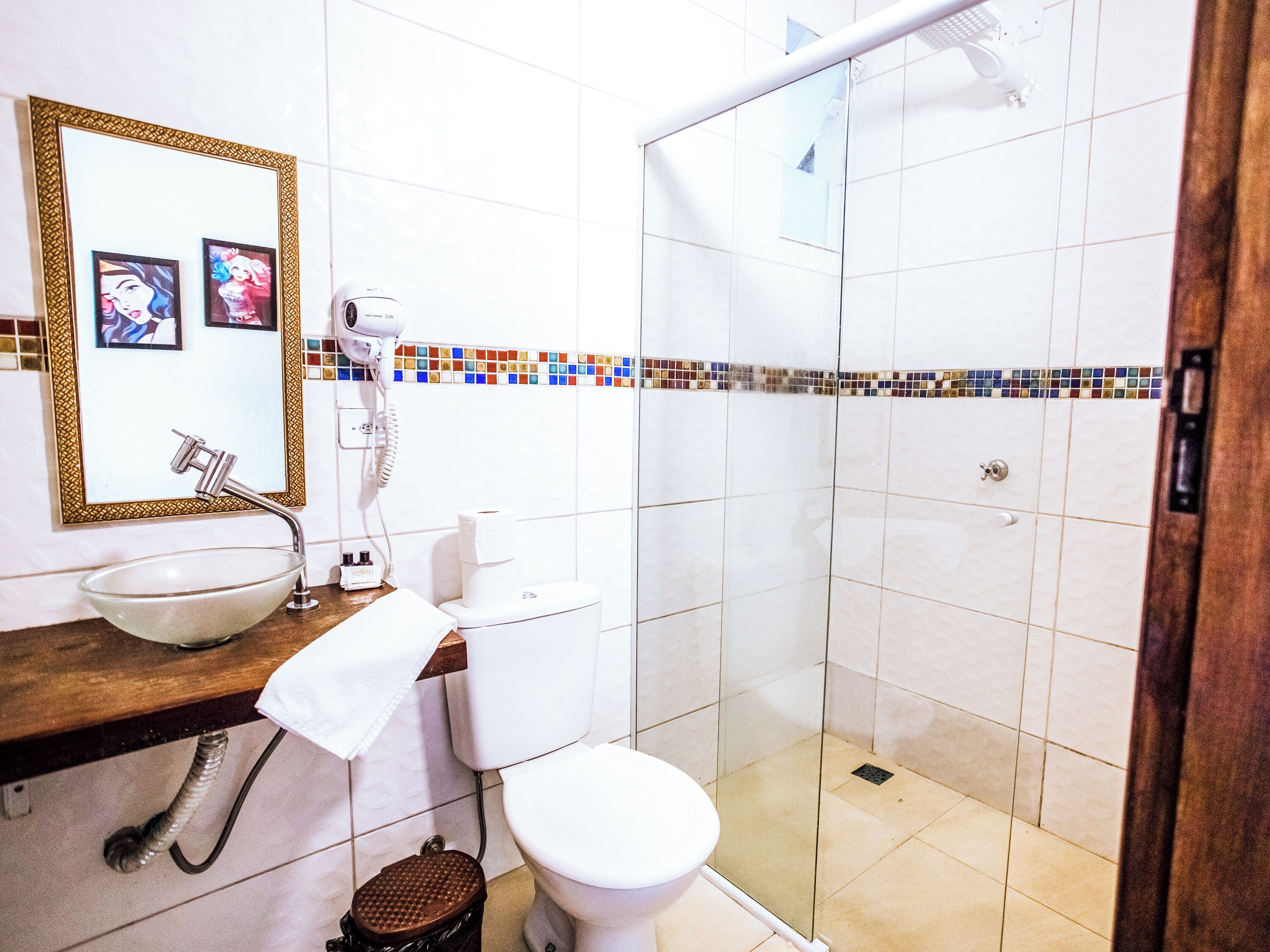 A bathroom with a glass shower enclosure, a sink with a mirror, and a toilet.