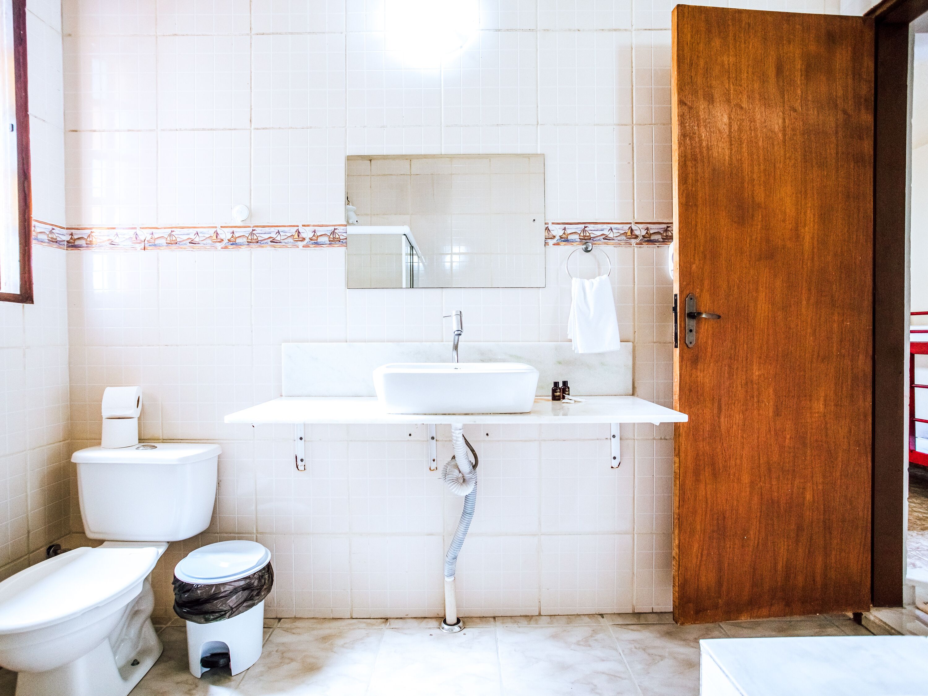 Een badkamer met toilet, bidet, wastafel en een houten deur.
