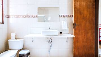 Een badkamer met toilet, bidet, wastafel en een houten deur.