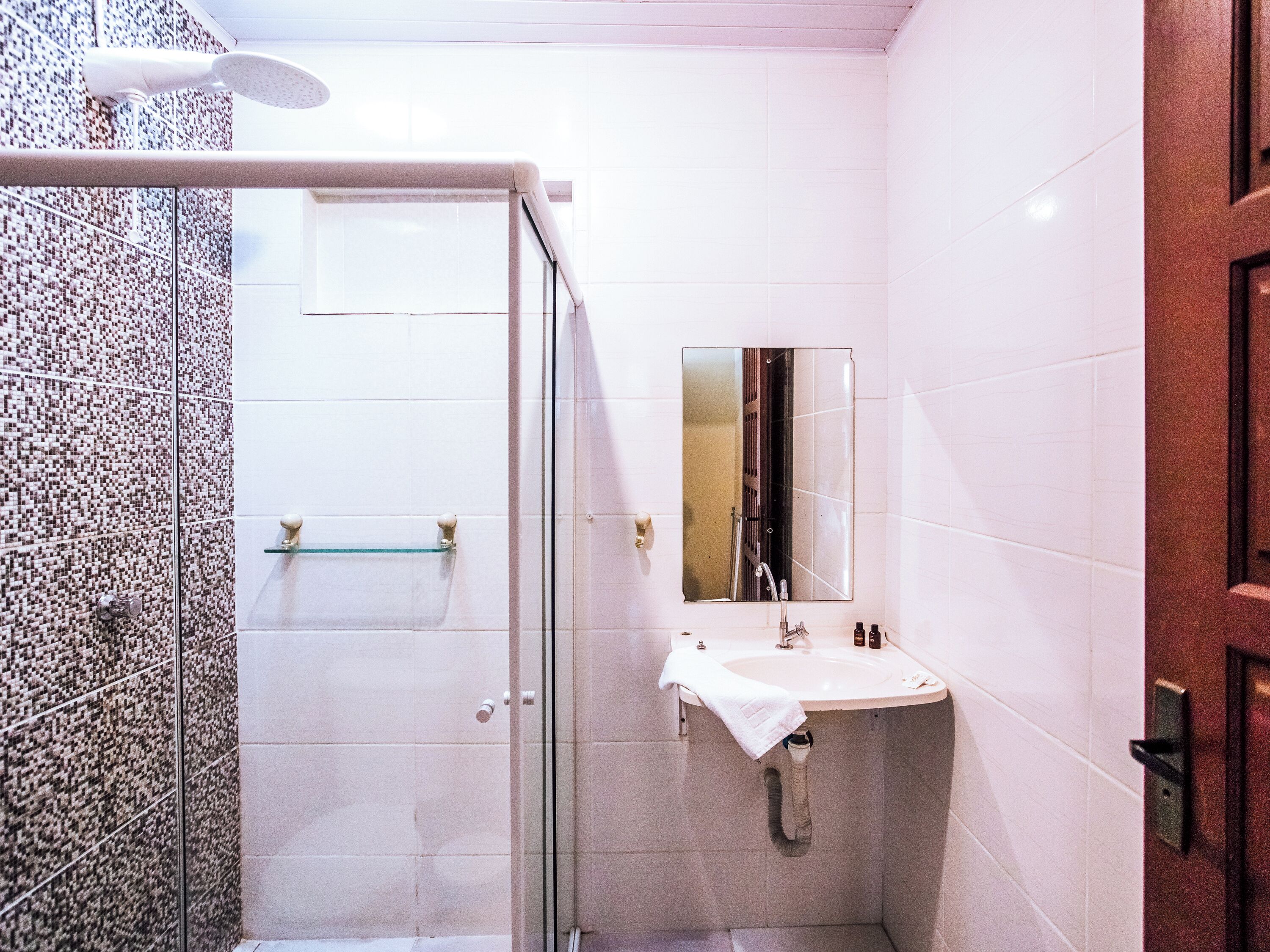 Un baño con ducha, lavamanos y espejo.