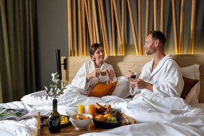 A hotel room with a bed, breakfast tray, and a wooden wall design. - Hôtel Belaroïa (Montpellier)