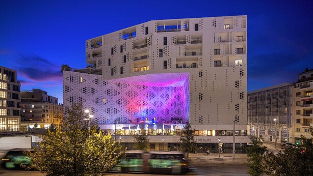 A modern building with balconies and illuminated windows at night.