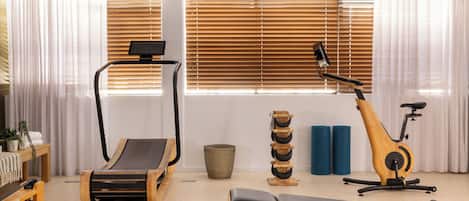 A gym with exercise equipment, including a treadmill, stationary bike, and bench.