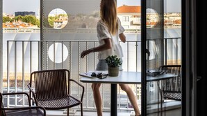 A balcony with a table, chairs, and a potted plant.