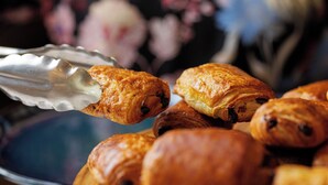 A plate of pastries with a person using tongs to pick one up.