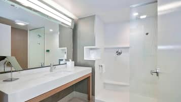 A modern bathroom with a large mirror, two sinks, a shower, and a glass-enclosed shower area.