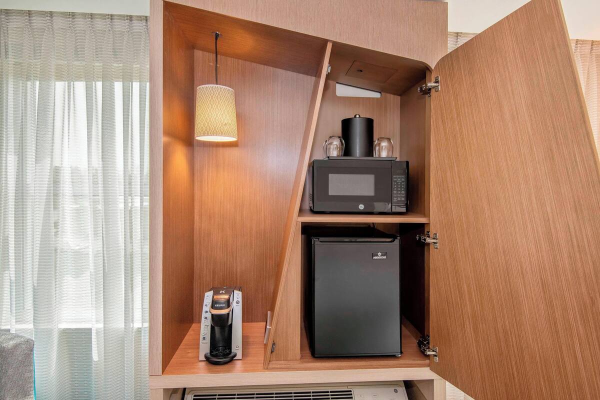 A compact kitchenette with a microwave, a small refrigerator, and a coffee maker.