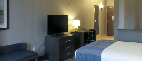 A hotel room with two beds, a TV, a desk, and a chair.