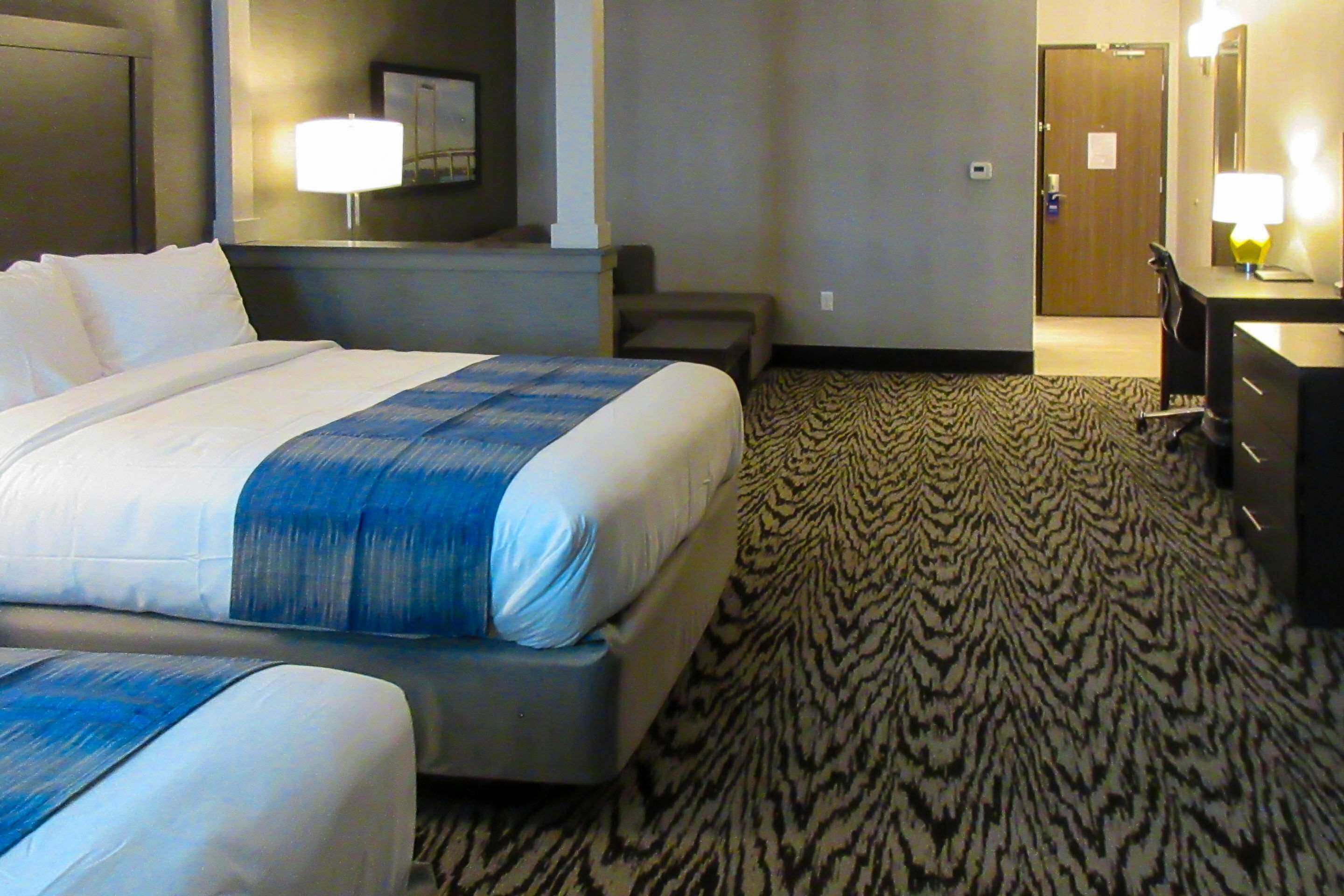 A hotel room with a large bed, a desk, and a chair.