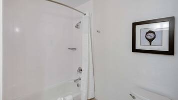 Un bagno con una vasca, un water e una cornice con un orologio appeso al muro.