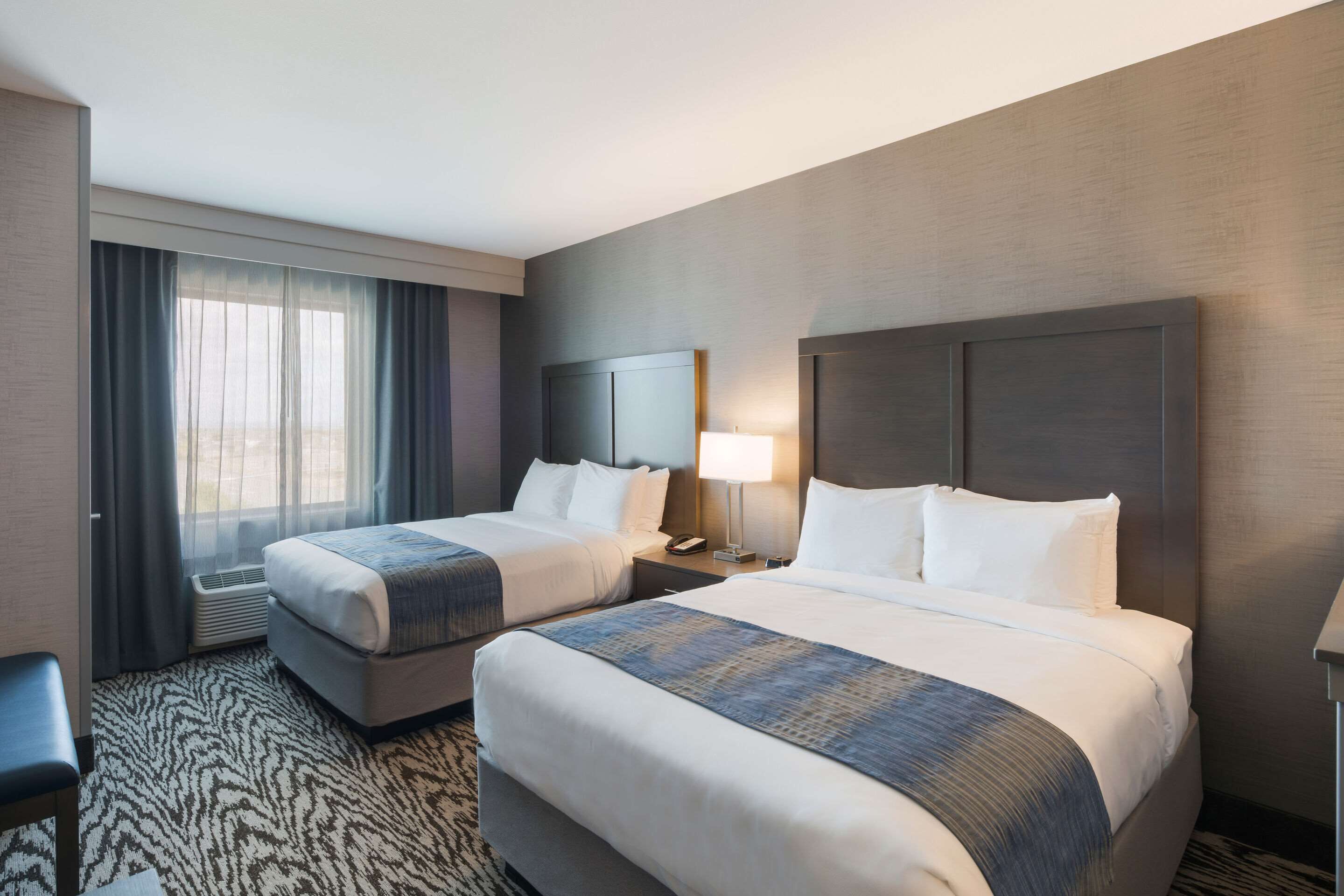 A hotel room with two beds, a desk, and a chair.