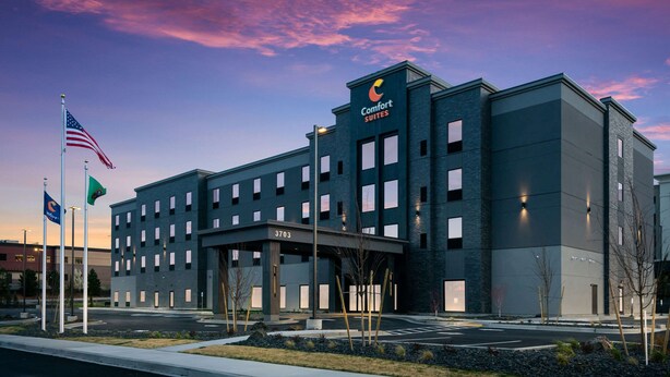 Un hotel moderno con techo plano, varias ventanas y un letrero que indica que es un Comfort Suites.