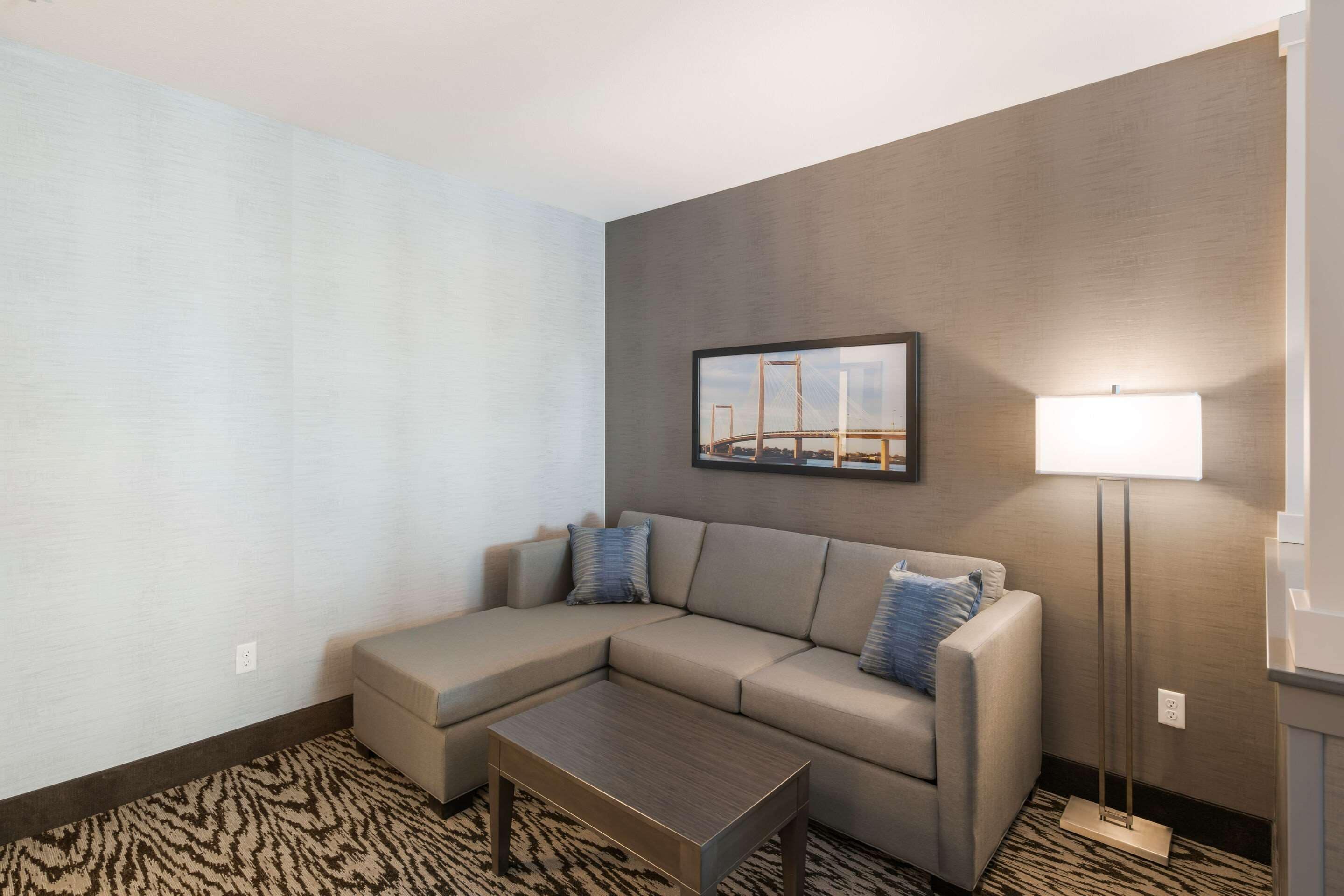 A modern living room with a sectional sofa, a small coffee table, and a floor lamp.