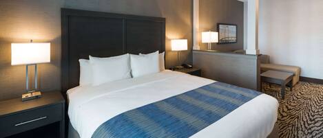 Een hotelkamer met een groot bed, twee nachtkastjes met lampen, een klein bureau en een stoel.