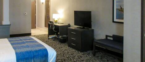A hotel room with two beds, a desk with a chair, a television, and a framed picture on the wall.