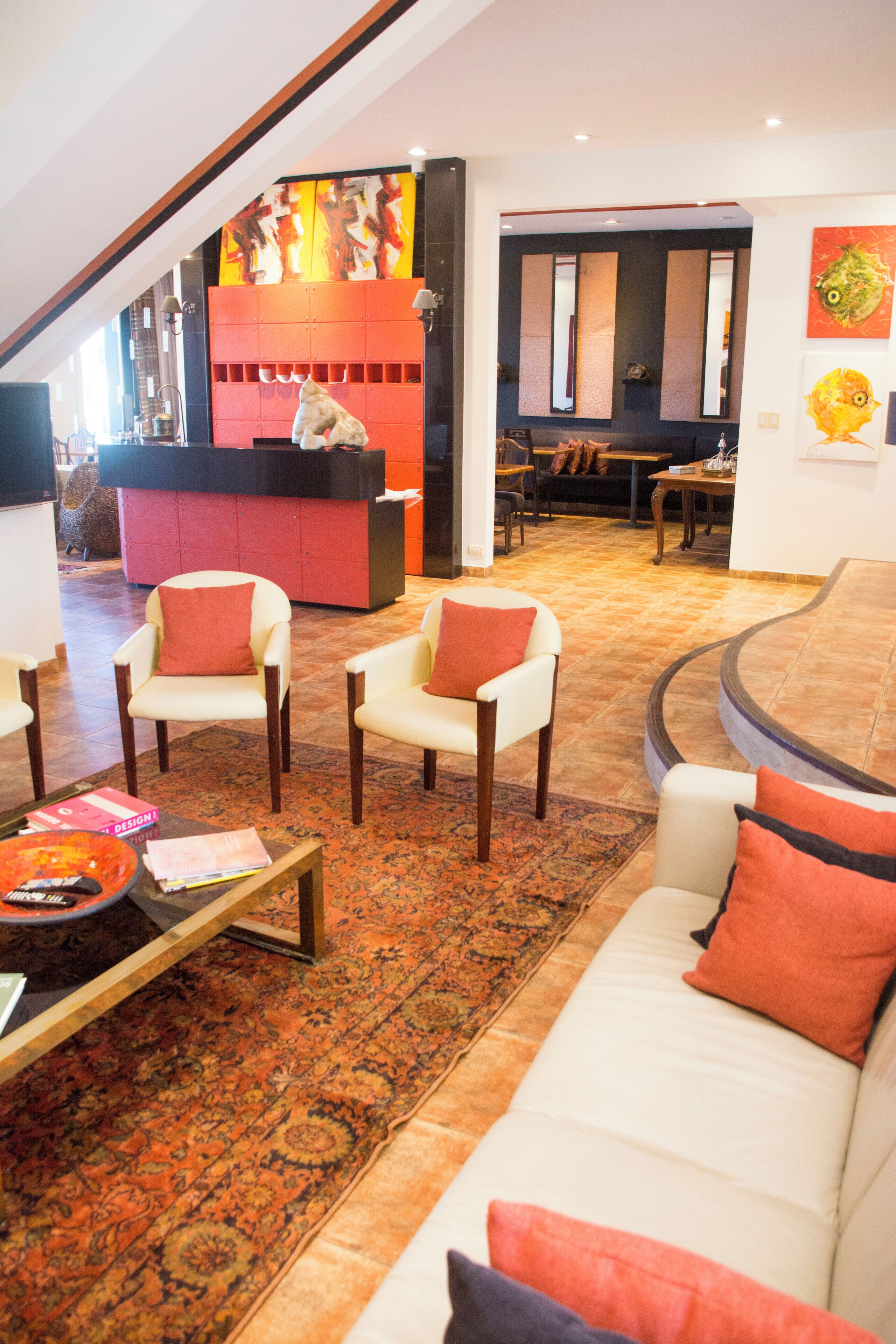 Un amplio salón con sofá, sillones y una mesa de centro. Se ve un mostrador de recepción al fondo.