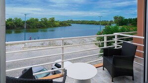 A balcony with a view of a river, a white table, and two black chairs. - Hotel Boutique Los Muelles (Carmelo)