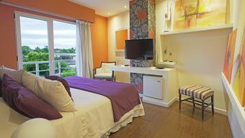 Habitación de hotel con cama, escritorio, televisor y vistas a zonas verdes.