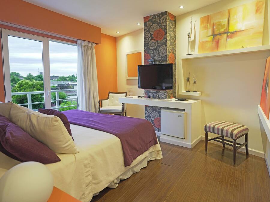Habitación de hotel con cama, escritorio, televisor y vistas a zonas verdes.