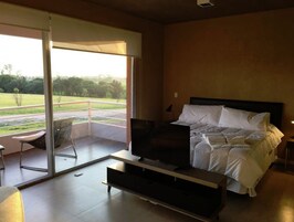 Un dormitorio con cama, televisión y balcón con una silla.