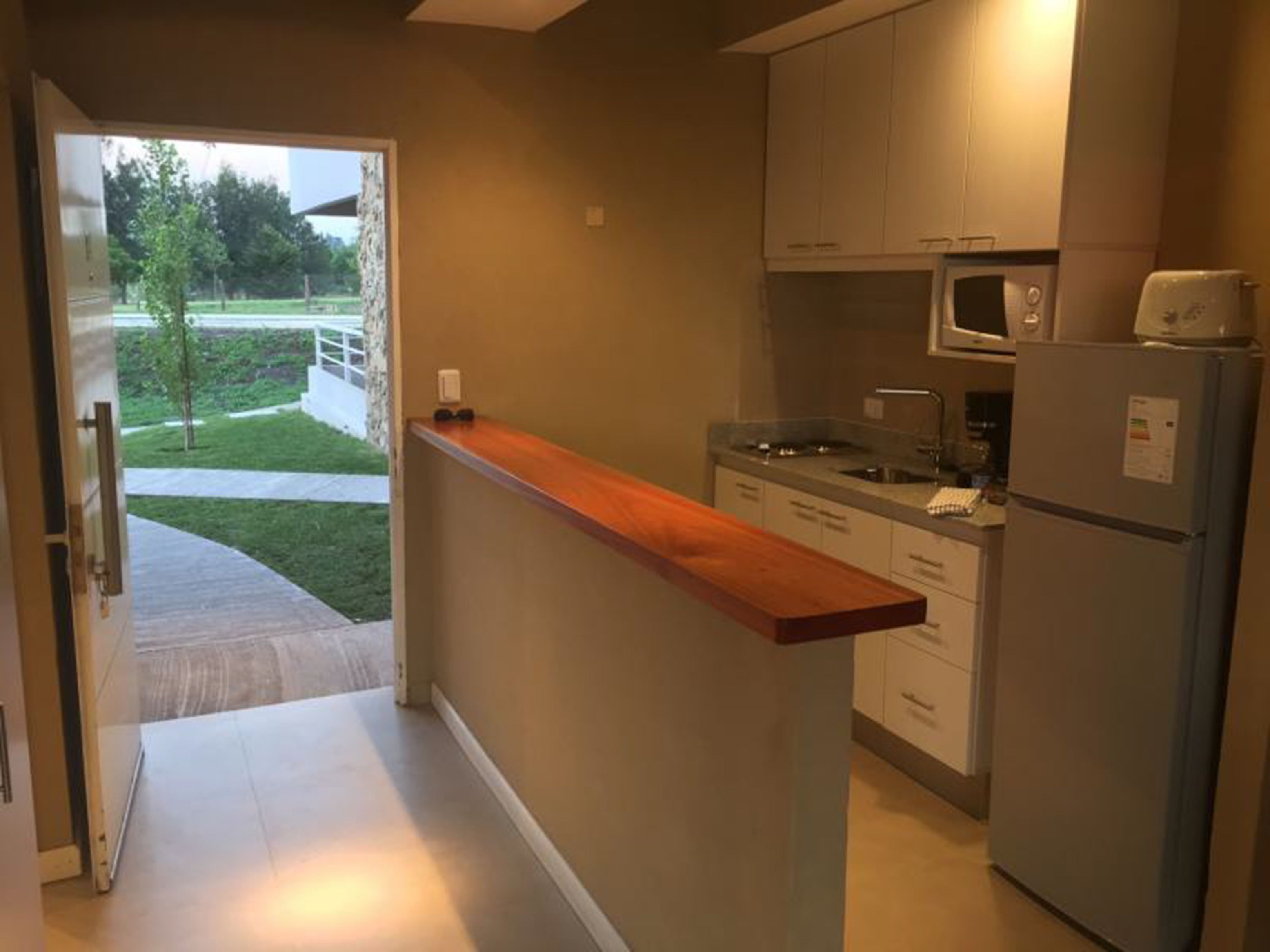 A modern kitchen with a wooden countertop, white cabinets, a microwave, and a refrigerator.