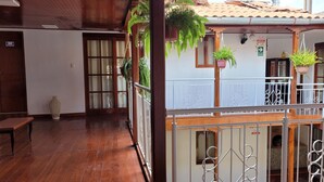 A wooden-floored corridor with a bench, a door with an SS.MH sign, and a white wall with a window and a door. - Casa Kuelap Hostal (Chachapoyas)
