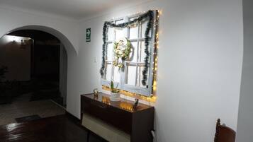 A room with a wooden dresser, a mirror, and a window decorated with a wreath and lights.