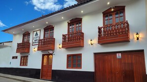 A building with multiple balconies, a sign reading "Hostal," and a large wooden door. - Casa Kuelap Hostal (Chachapoyas)
