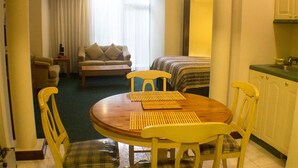 Une chambre d’hôtel compacte comprenant un coin repas, un canapé et une kitchenette.