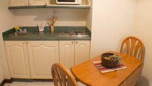 Une petite cuisine équipée d’un four à micro-ondes, d’une cuisinière et d’une table à manger avec des chaises.