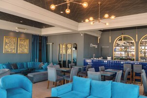 Zona de bar moderna con asientos azules y una barra mostrando varias botellas.