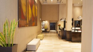A hotel lobby with a tiled floor, a reception desk, a large abstract painting, and a potted plant. - Premium Tower Suites (Mendoza)