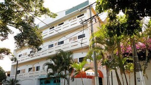 A multi-story hotel with a prominent turquoise entrance, surrounded by lush greenery and palm trees. - Hotel Miramonte & apartments (San Salvador)